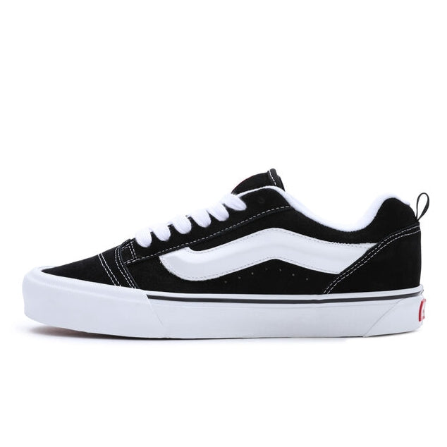 Main product image of the Vans Knu Skool black pairs. This image shows the side of the shoe featuring a thick vans line and the white rubber sole and a black suede upper.